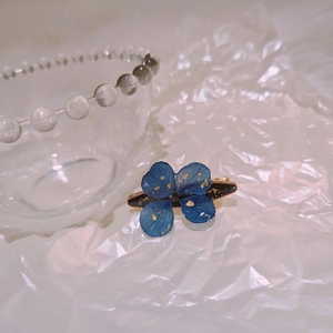 Handmade dark blue floral hair clip with gold foil accents on a black base