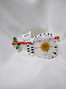 Détail de la broche chat artisanale avec marguerite blanche et feuilles sur soie
