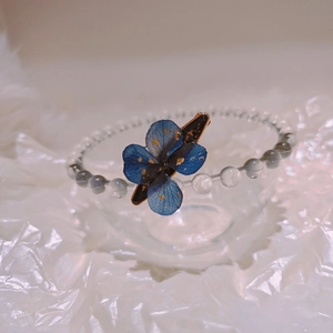 Macro detail of handmade resin bracelet with dried flower, gold foil and grey beads