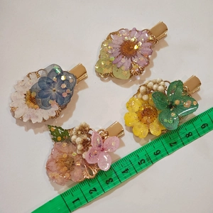 Detailed view of handmade resin flower hair clips with gold metal base and dried petals