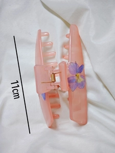 Close-up of 11cm pink resin hair claw clip with purple dried flower petal details