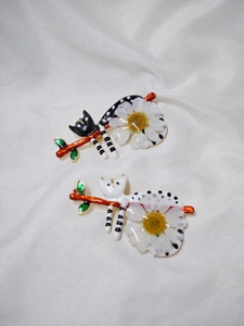 Détail de broches chat avec marguerites sur soie montrant la texture de l'émail fin