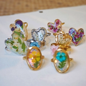 Detail view of handmade resin rings with real dried flowers and gold foil accents