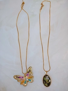 Détail de pendentifs papillon colorés et floraux sur chaînes serpent dorées