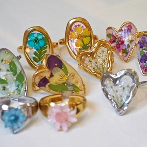 Detail of handmade resin open rings with real dried flowers and gold foil accents