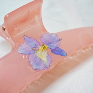 Elegant translucent pink hair claw clip featuring purple dried flowers and gold accents