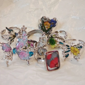 Detail of handmade resin rings featuring colorful dried flower petals and butterfly shapes