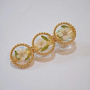 Barrette en résine avec fleurs séchées blanches et bordure dorée torsadée