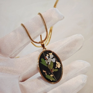 Collier avec pendentif ovale fleur séchée blanche et feuilles d'or sur chaîne serpent dorée