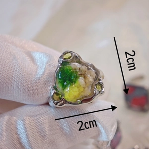 Macro detail of handmade resin ring featuring yellow dried flowers and silver band
