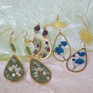 Detail van handgemaakte hars oorbellen met echte droogbloemen en goudkleurige legering
