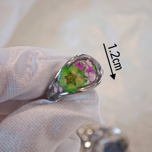 Macro detail of teardrop resin ring with real green and purple flowers, 1.2cm size