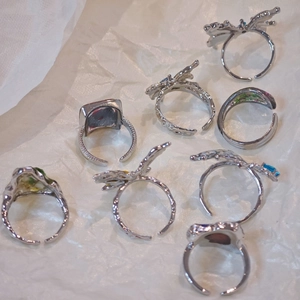 Detail of silver rings set with butterfly designs and colorful dried flower accents