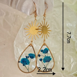 Handgemaakte etnische hars oorbellen met blauwe droogbloemen en gouden zon hanger