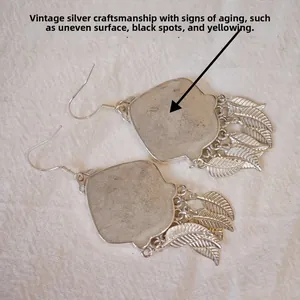 Detailed macro view of retro silver ethnic earrings with fringe leaf pendants and old process