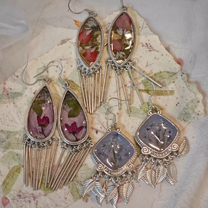 Detailed macro view of bohemian resin earrings with dried flowers and silver tassels