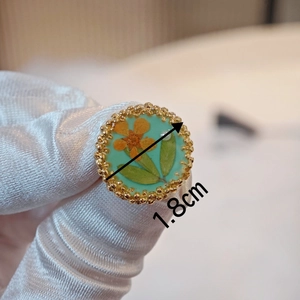 Macro shot of a 1.8cm handmade Morandi turquoise resin ring featuring dried orange flowers
