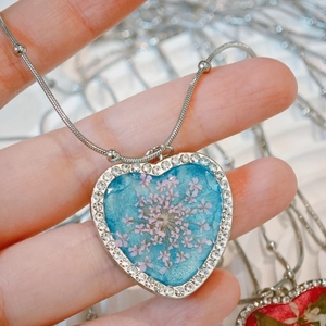 Macro detail of heart pendant necklace with pink dried flower and sparkling rhinestones