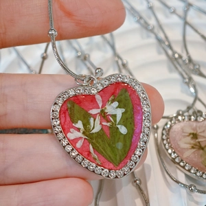 Detailed macro of heart pendant with real dried flowers and sparkling rhinestones