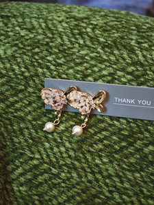 Detail of gold butterfly bow earrings with pink dried flowers and white pearls