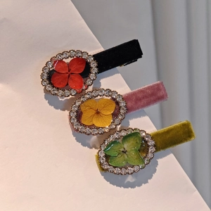 Detail view of velvet hair clips with embedded real flowers and sparkling rhinestones