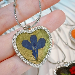 Detail of heart pendant with real blue dried flower and sparkling zircon border