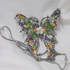 Macro shot of silver butterfly necklace featuring real dried flowers in resin inlay