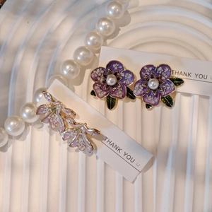 Vintage style floral resin earrings with purple petals and pearl center on display card