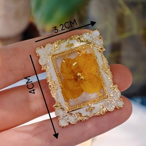 Detailed view of a 3.2cm x 4cm vintage French floral brooch with yellow dried flowers