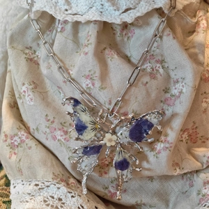 Collana artigianale con ciondolo a farfalla e vere fioriture viola essiccate in resina