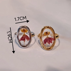 Detail of handmade stainless steel rings featuring real dried flowers in oval resin