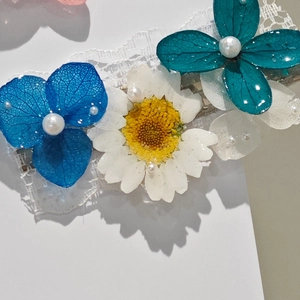 Close-up of blue hydrangea and white daisy hair clip with lace and pearl details