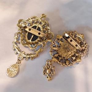 Detailed back view of vintage gold-plated brooches showing intricate hollow metalwork