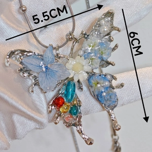 Handmade oversized butterfly pendant with blue dried flowers and pearls measuring 5.5 by 6 cm