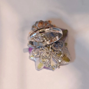 Macro view of silver adjustable ring with flower patterned prop on white fabric