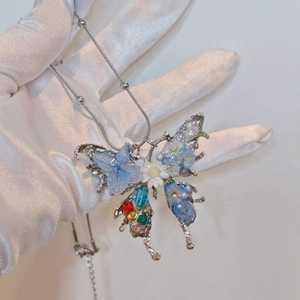 Handmade butterfly pendant necklace with blue dried flowers and beads on silver chain