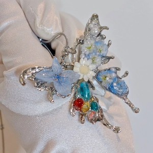 Detailed macro shot of a butterfly pendant with real blue dried flowers and mixed gemstones