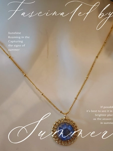 Detailed shot of handmade gold floral necklace with blue dried flower resin pendant