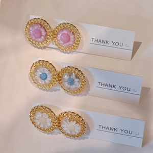 Detailed macro view of handmade daisy resin stud earrings in pink, blue, and white colors