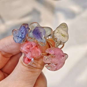 Gros plan de bagues artisanales en résine avec de véritables pétales de fleurs séchées