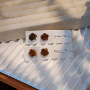 Handmade coffee bean stud earrings in gold and silver settings on white card