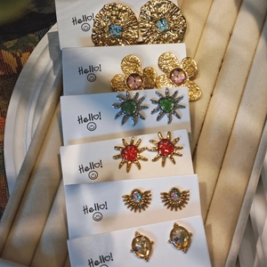 Handmade stainless steel floral stud earrings set with colorful gemstones on display card