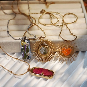 Detailed macro view of four handmade dried flower resin pendants on gold and silver chains