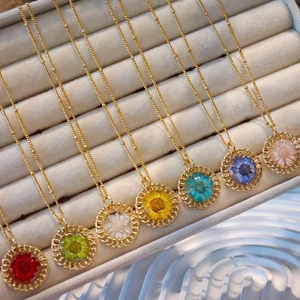 Detail showing seven handmade necklaces with real dried flowers in gold openwork pendants