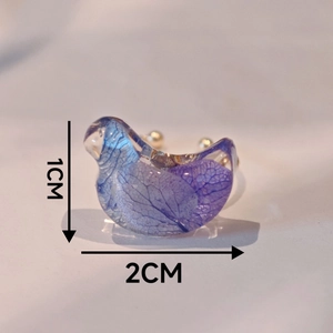 Vue macro de la bague oiseau en résine avec fleur d'hortensia violette, dimensions 1x2cm