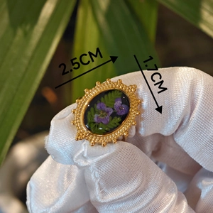 Detailed macro of oval vintage floral resin ring featuring purple real dried flowers