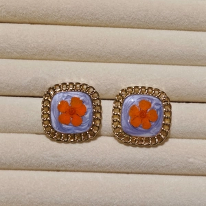 Macro shot of square vintage earrings with orange dried flowers and gold hollow frames