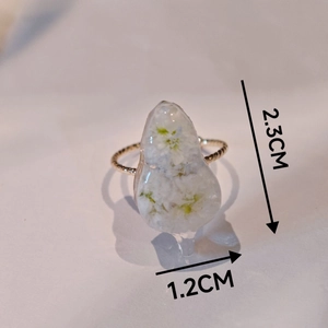 Vue macro détaillée de la bague en résine avec fleurs blanches séchées et anneau doré