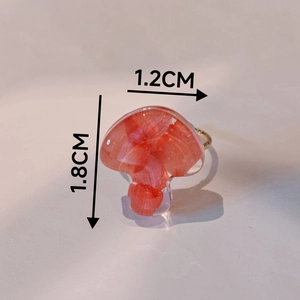 Détails d'une bague en résine en forme de champignon avec fleurs rouges et anneau doré