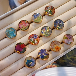 Macro view of handmade resin rings with real dried flowers in gold stainless steel bases